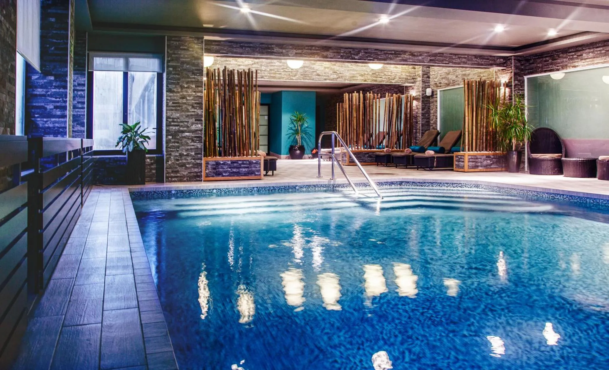 Une piscine intérieure avec des transats et des plantes.