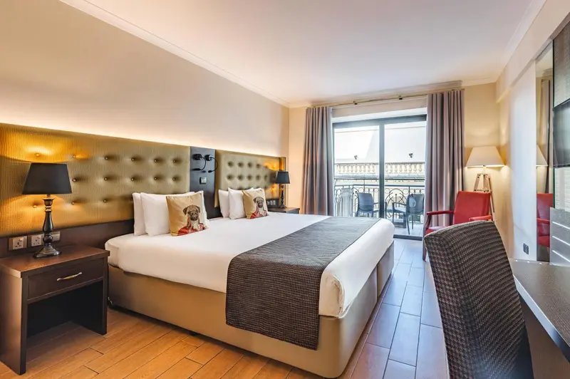 Chambre lumineuse avec un grand lit et un balcon.