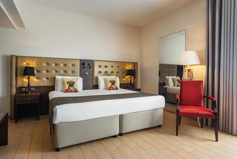 Chambre lumineuse avec un grand lit et un fauteuil rouge.