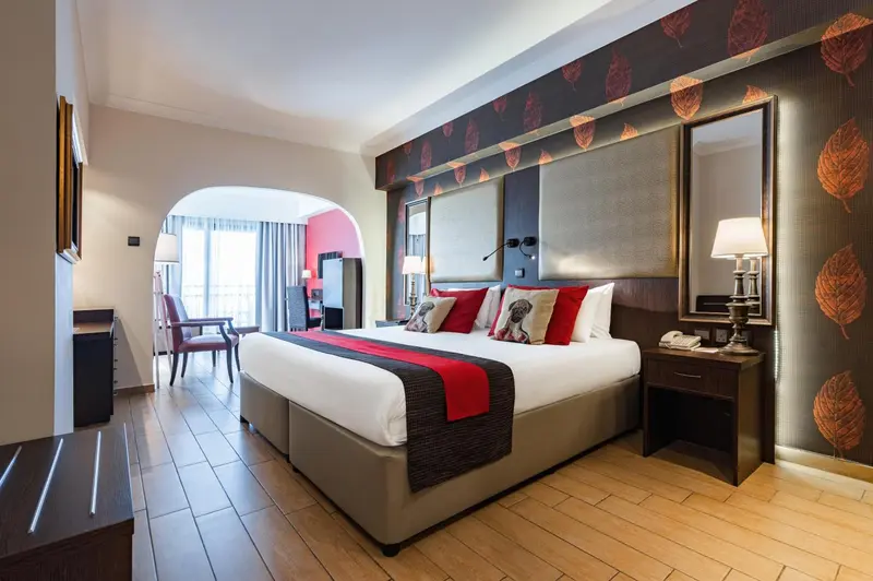 Une chambre lumineuse avec un grand lit et un décor mural stylisé.