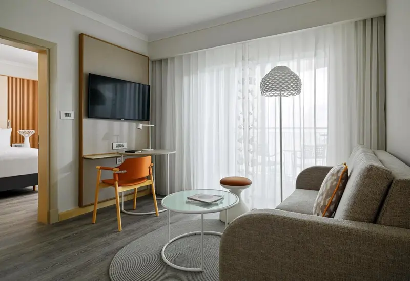 Une chambre lumineuse avec un coin salon et un bureau.