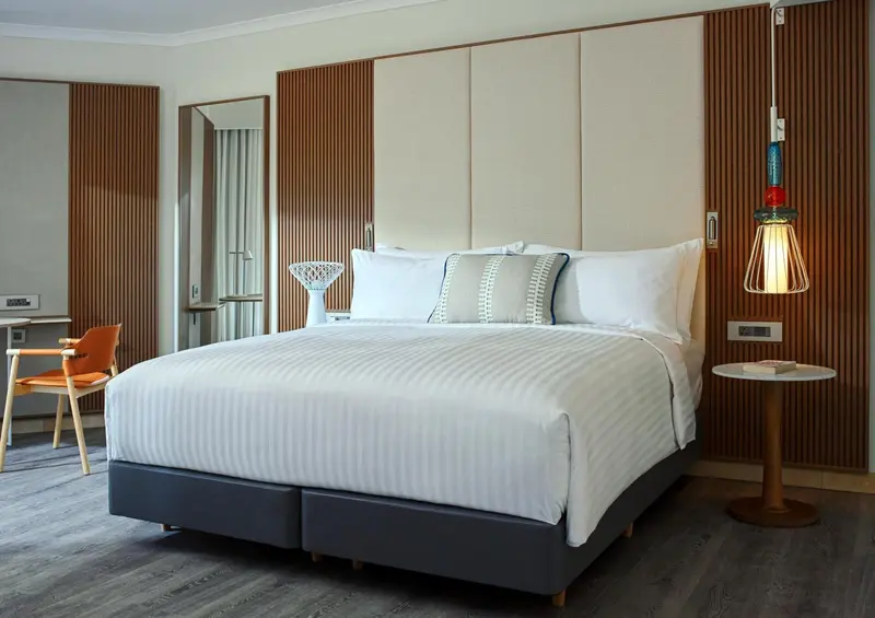 Une chambre lumineuse avec un grand lit recouvert d'une courtepointe blanche et de coussins.