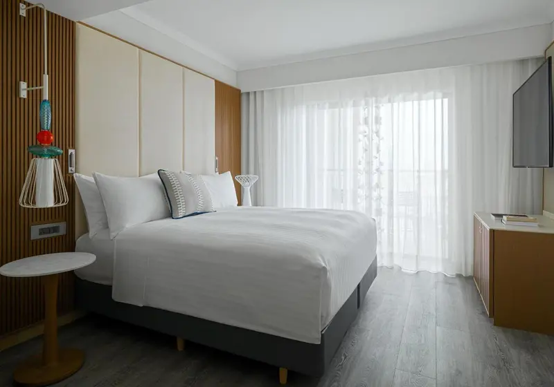 Une chambre lumineuse avec un grand lit et des rideaux blancs.