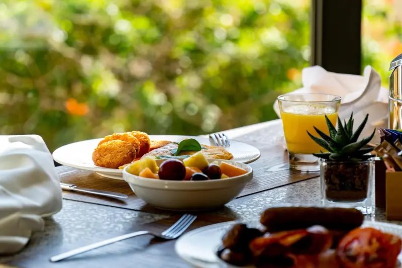 Un petit-déjeuner copieux est présenté sur une table avec une vue verdoyante.