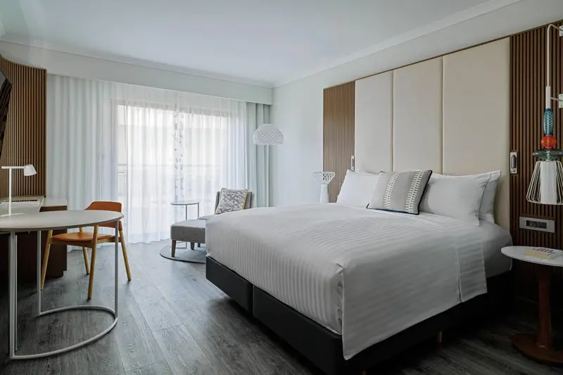 Une chambre lumineuse avec un grand lit et un coin repas.