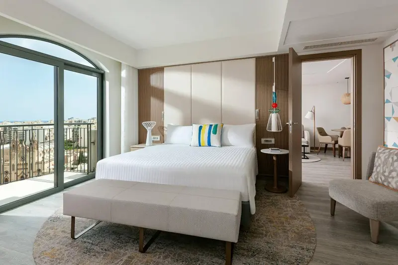 Une chambre lumineuse avec un grand lit et un accès à un balcon.