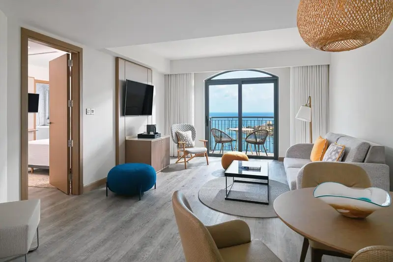 Un salon lumineux avec canapés et table basse offre une vue sur la mer.