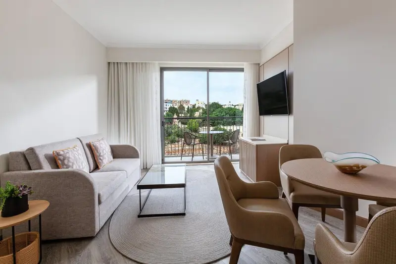 Un salon clair s'ouvre sur une terrasse avec vue sur la vegetation.
