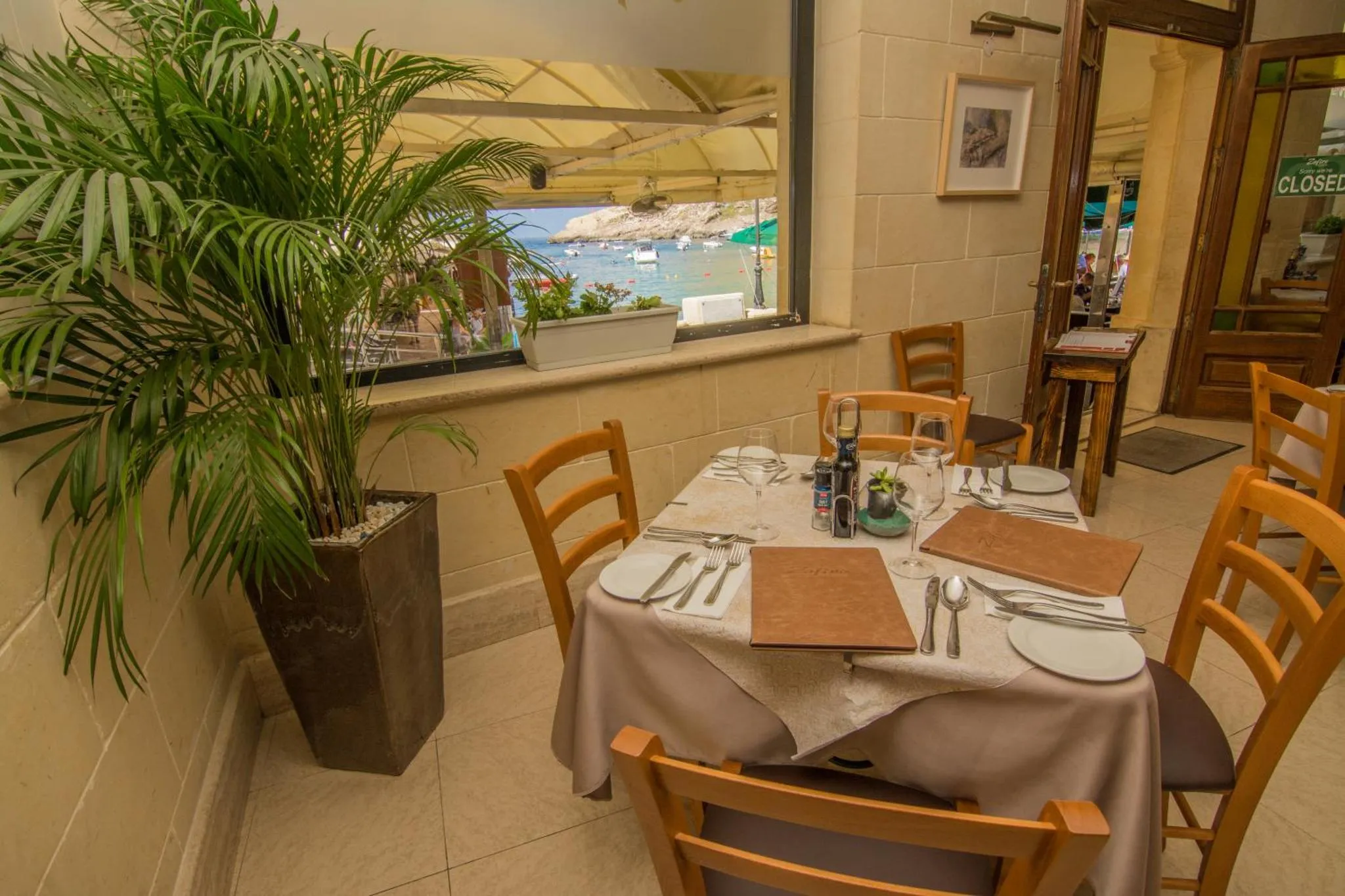 Une salle à manger lumineuse avec des tables dressées et une vue sur la mer.