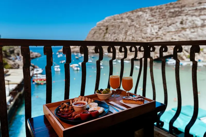 Un petit-déjeuner est servi sur une table de balcon avec vue sur une baie.