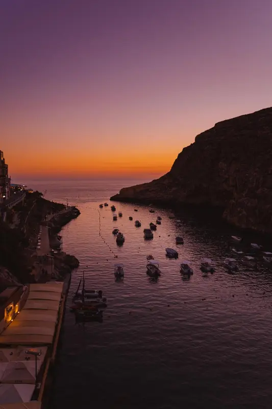 Une anse abritée avec de nombreux petits bateaux amarrés au coucher du soleil.