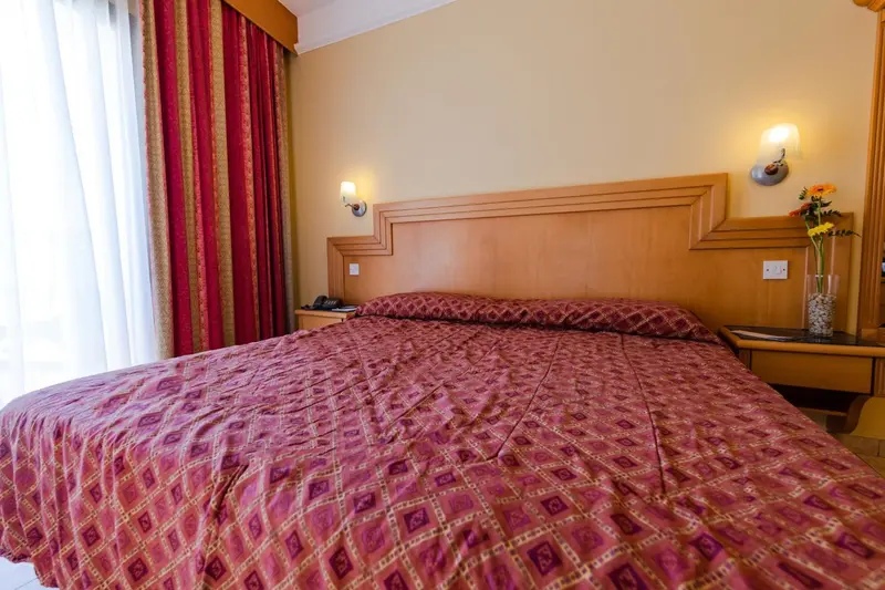 Une chambre avec un grand lit recouvert d'une courtepointe et des rideaux rouges.