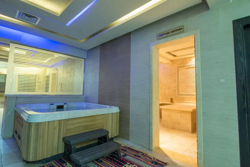 Un jacuzzi d'angle dans une salle de bain lumineuse avec un accès à un espace de détente.