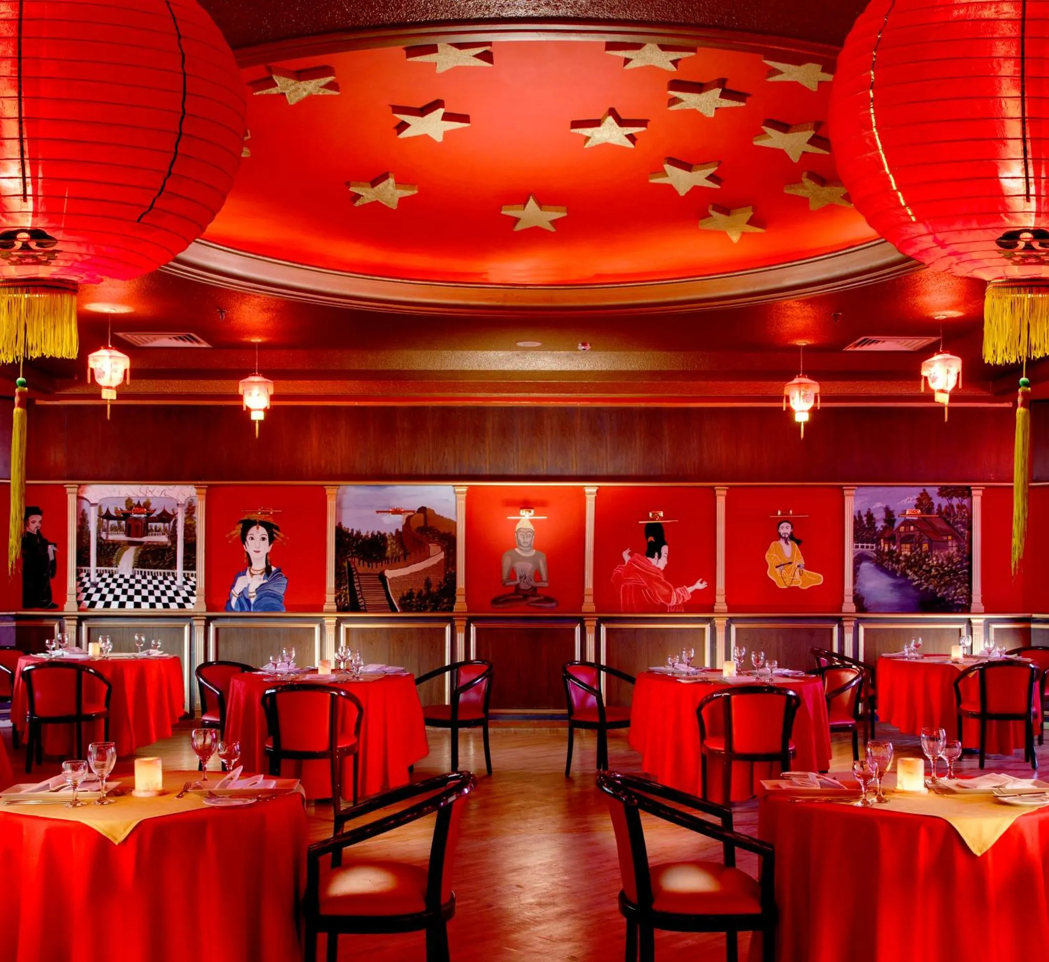 Une salle de restaurant décorée de lanternes rouges et d'œuvres d'art murales.