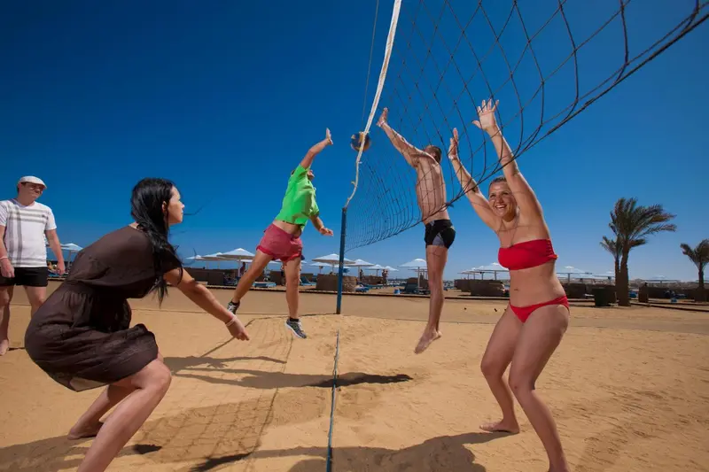 Des personnes jouent au volley-ball sur une plage de sable fin.