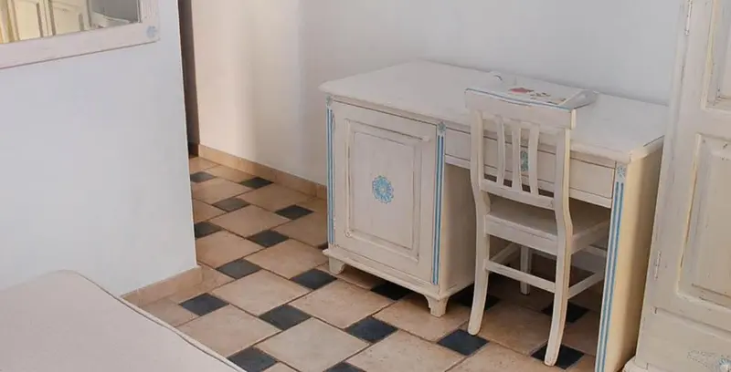 Une commode blanche et une chaise en bois se trouvent dans une pièce carrelée.