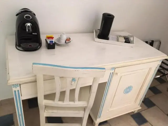 Une machine à café et des accessoires sont posés sur un bureau en bois peint.