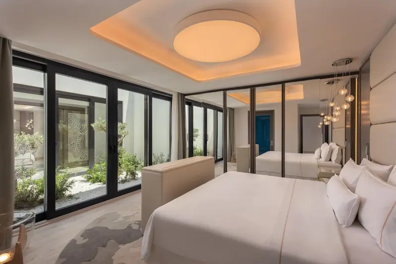 Une chambre lumineuse avec un grand lit et un accès à une cour intérieure.