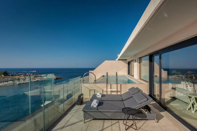 Terrasse avec jacuzzi et chaises longues donnant sur la mer.