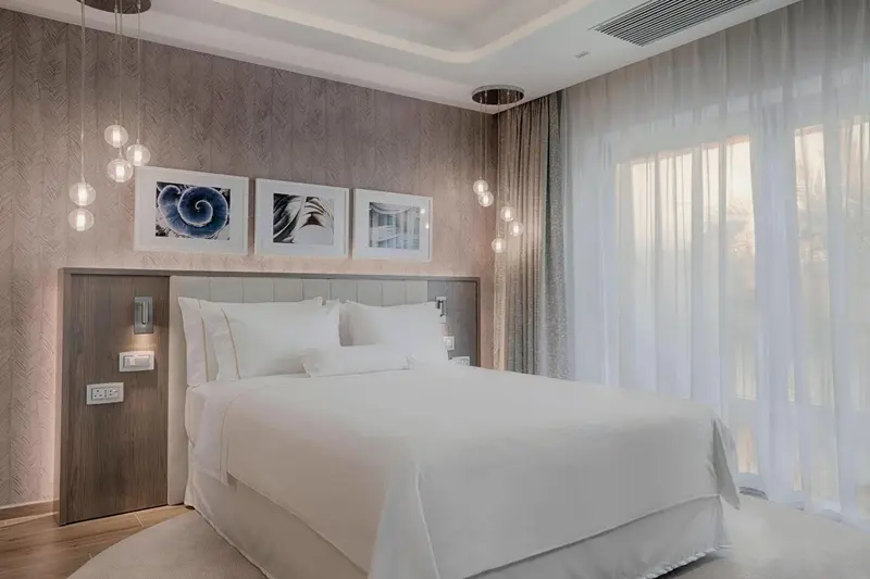 Une chambre lumineuse avec un grand lit et des tableaux décoratifs.
