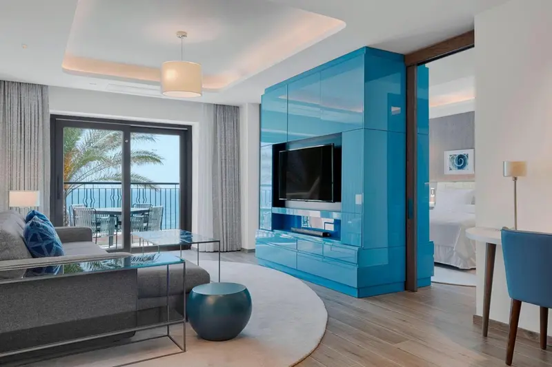 Interieur moderne avec canape gris, meuble bleu et vue sur la mer.
