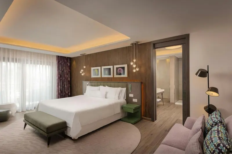 Une chambre lumineuse avec un grand lit et un espace salon.