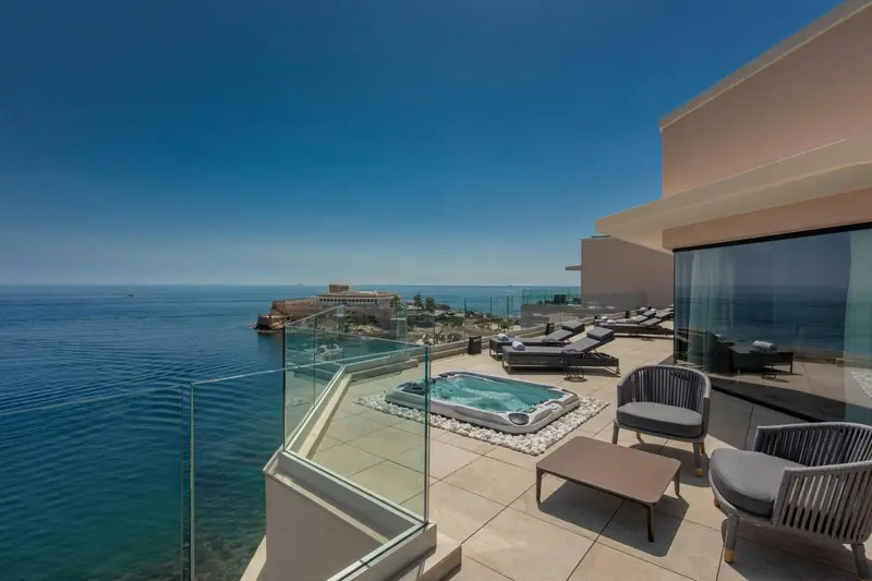 Terrasse avec jacuzzi et mobilier de jardin offrant une vue sur la mer.