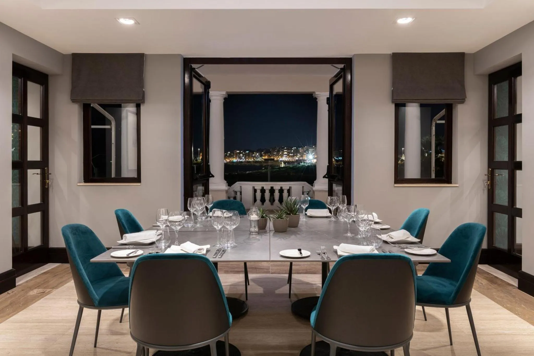 Une table de repas est dressée dans une salle lumineuse avec vue sur un paysage nocturne.