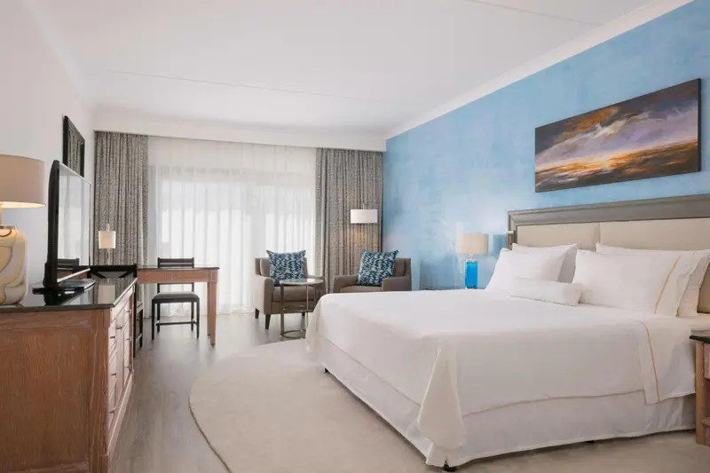 Chambre lumineuse avec un grand lit et un coin salon.