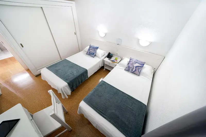 Une chambre avec deux lits simples et une table de chevet.