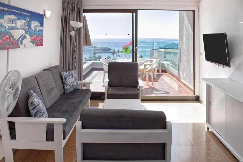 Un salon lumineux s'ouvre sur une terrasse avec vue sur la mer.