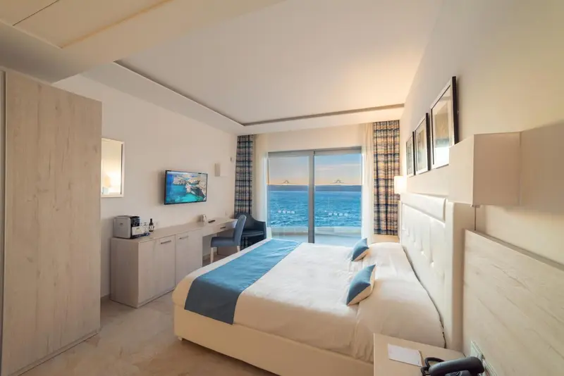 Chambre lumineuse avec un grand lit donnant sur la mer.