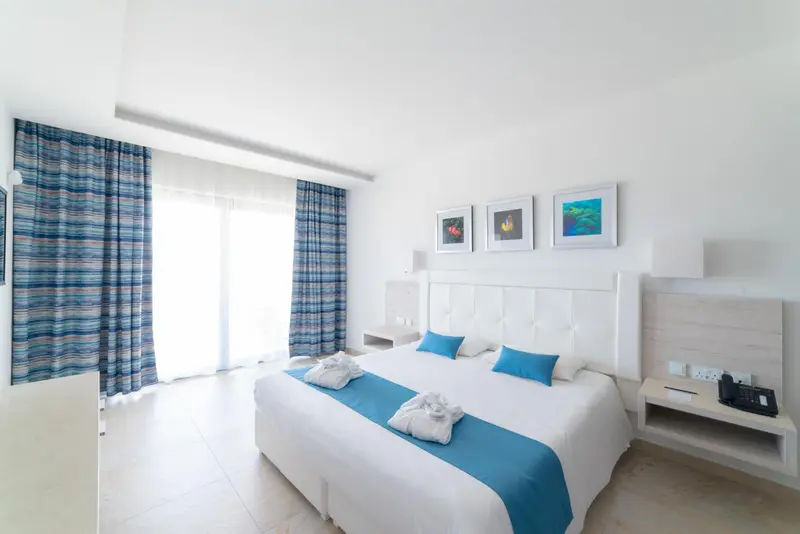 Une chambre lumineuse avec un grand lit et des rideaux bleus.