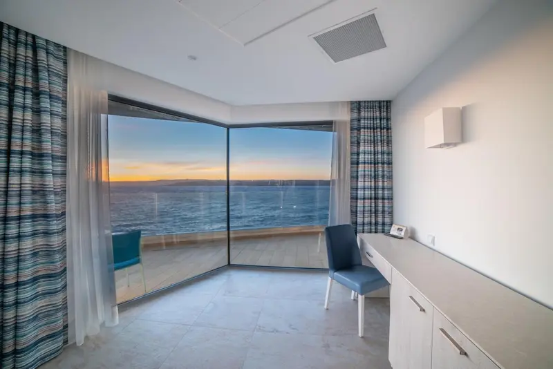 Une chambre lumineuse avec vue sur la mer au coucher du soleil.