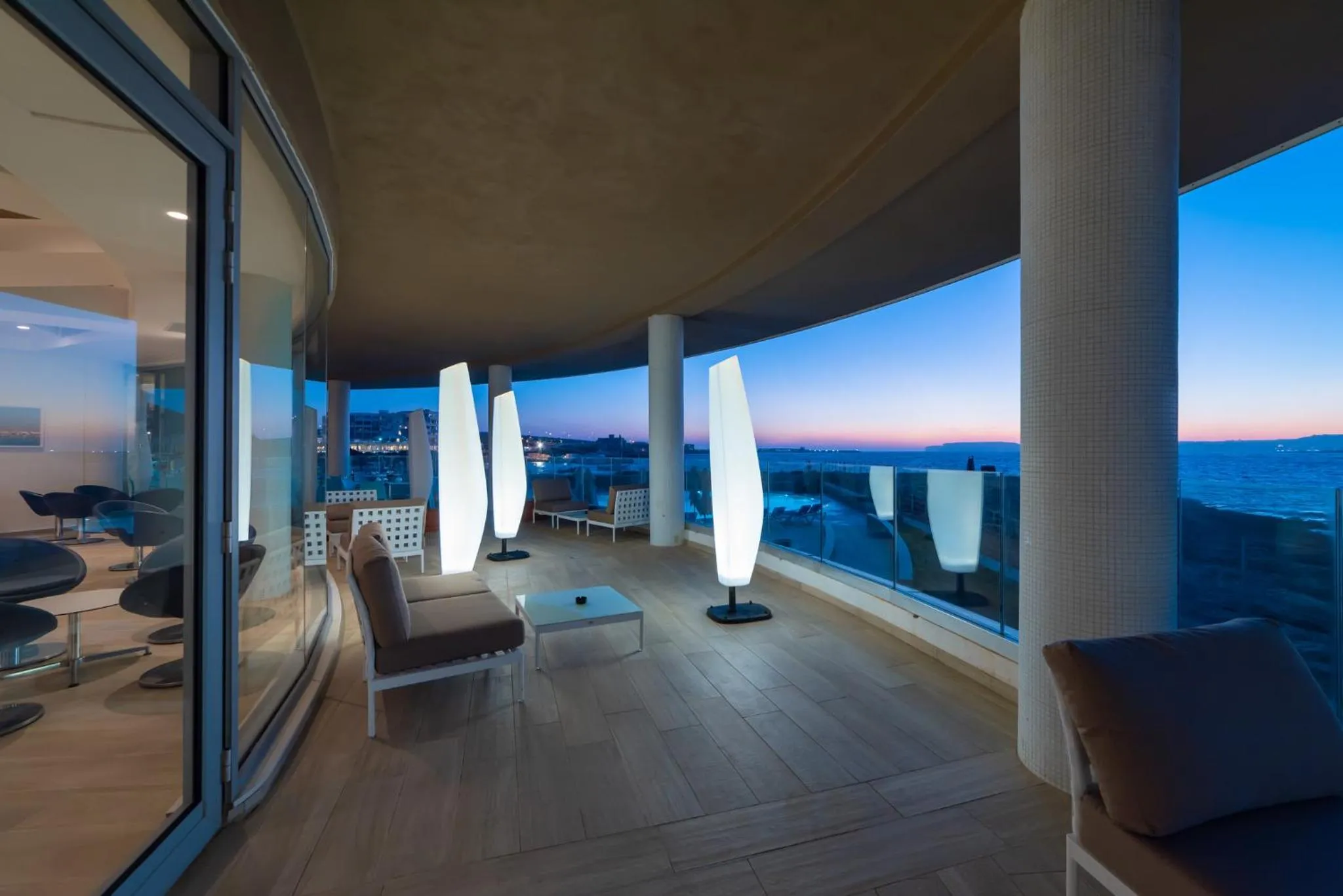 Terrasse moderne avec mobilier d'extérieur et vue sur la mer au crépuscule.
