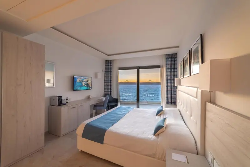 Chambre lumineuse avec un grand lit donnant sur la mer.