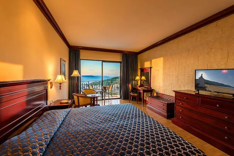 Chambre lumineuse avec un grand lit et une vue sur la mer.