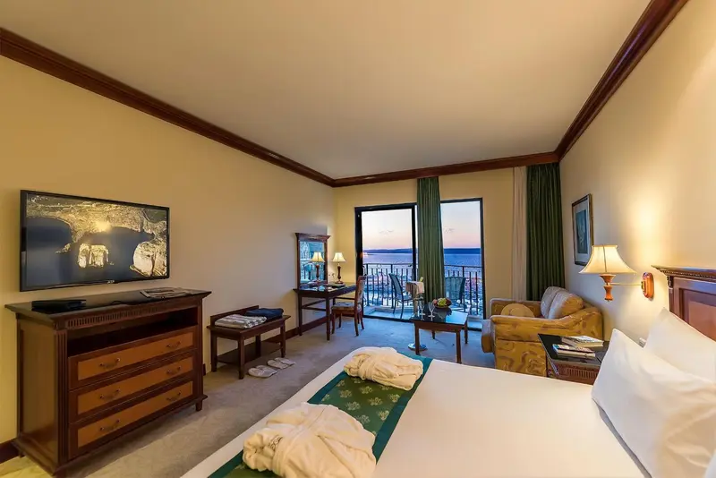 Une chambre lumineuse avec un lit, un canapé et une vue sur la mer.