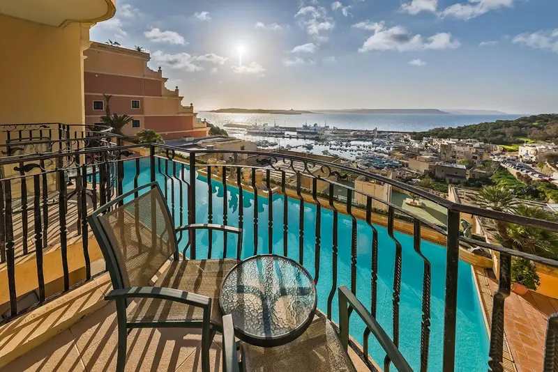Terrasse avec vue sur la mer et un port de plaisance ensoleillé.