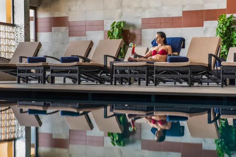 Une femme se relaxe sur un transat au bord d'une piscine.