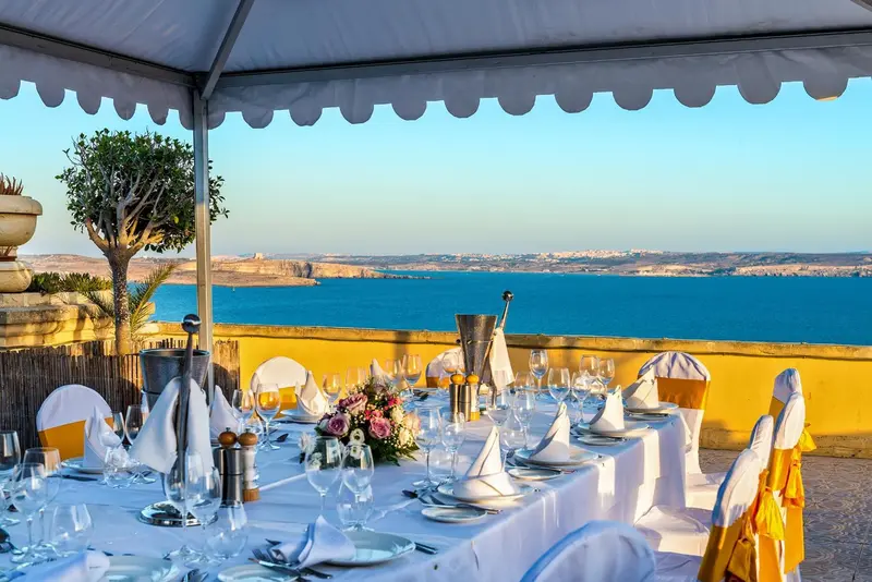 Une table dressée en extérieur offre une vue sur la mer et le littoral.