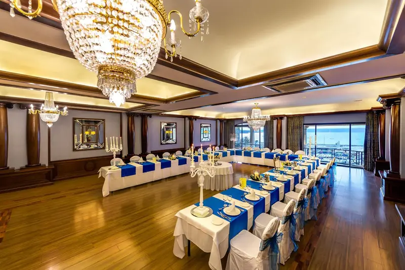 Une grande salle lumineuse est aménagée pour une réunion avec des tables disposées en U.