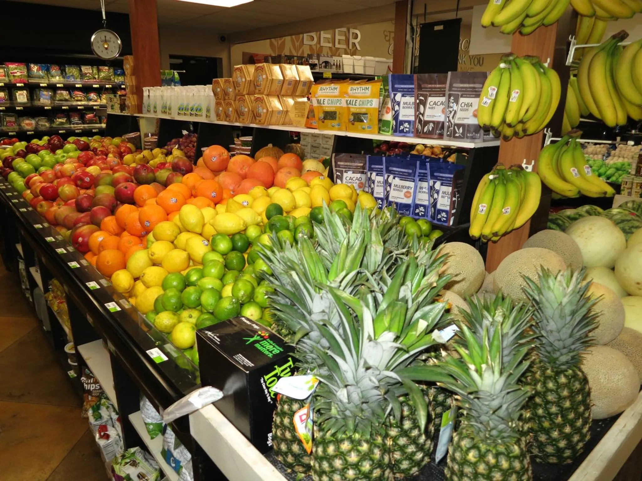 Un étalage coloré de fruits frais et de produits d'épicerie est présenté dans un magasin.