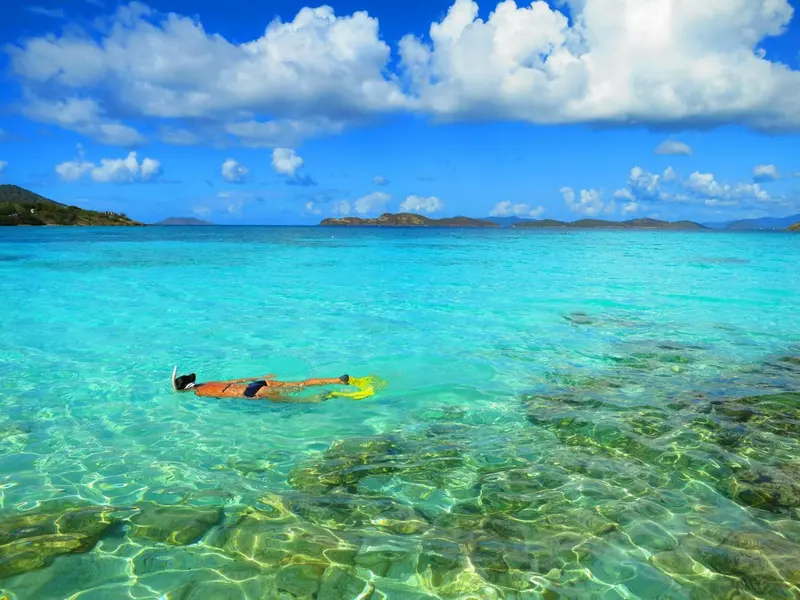 Une personne pratique le snorkeling dans une eau turquoise et claire.
