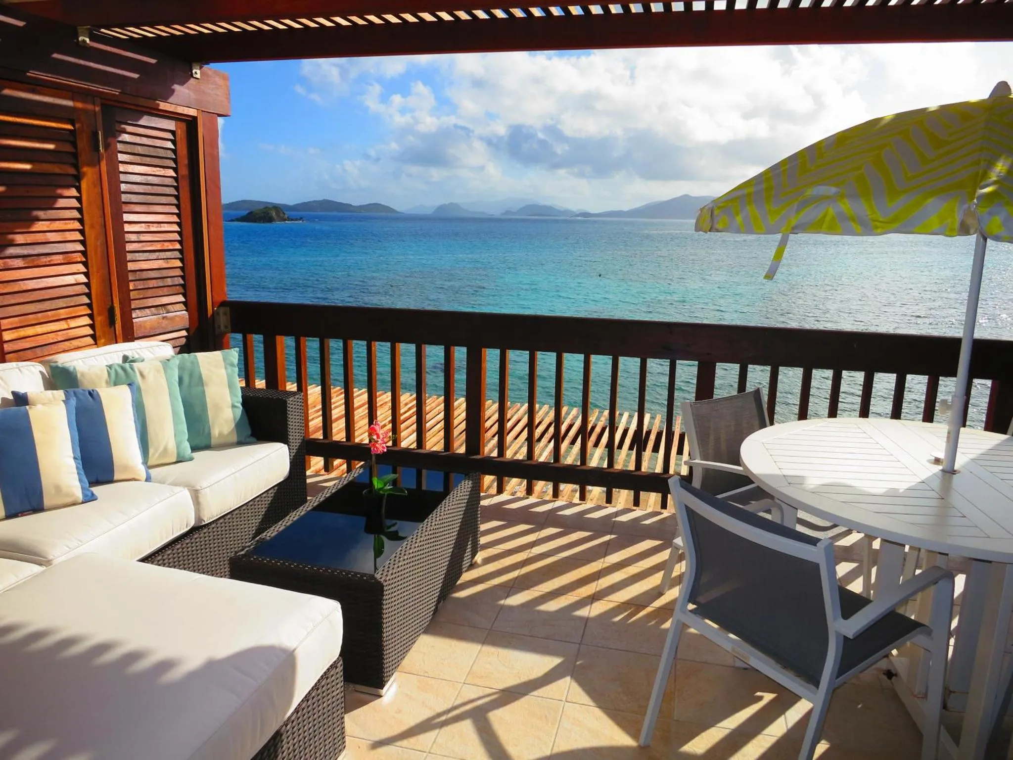 Terrasse aménagée avec canapés et table basse, vue sur la mer turquoise et les îles au loin.