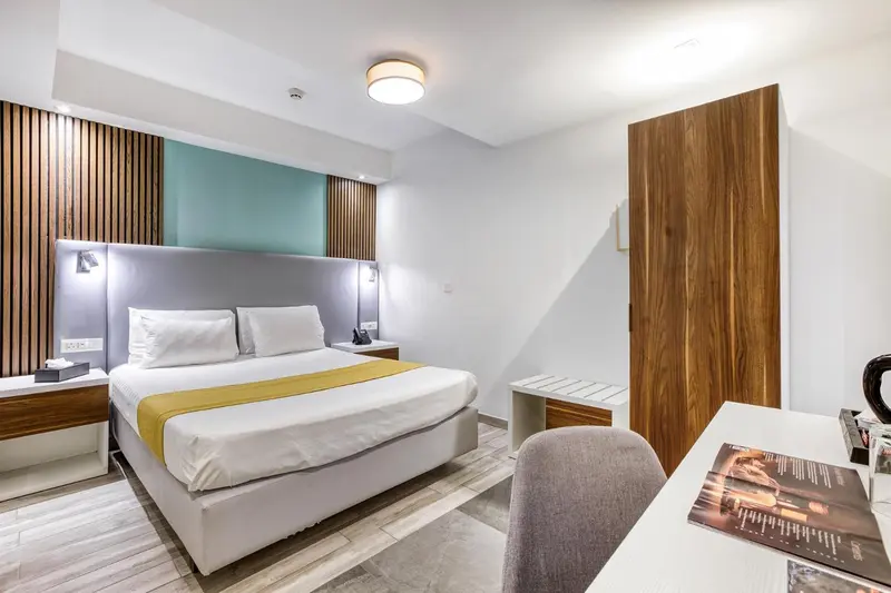 Une chambre lumineuse avec un grand lit et un bureau.