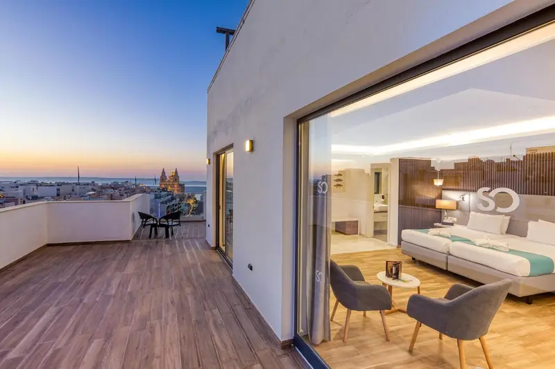 Terrasse aménagée avec salon et vue sur la ville au crépuscule.