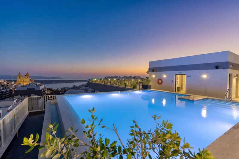 Piscine à débordement sur un toit avec vue sur la ville au crépuscule.