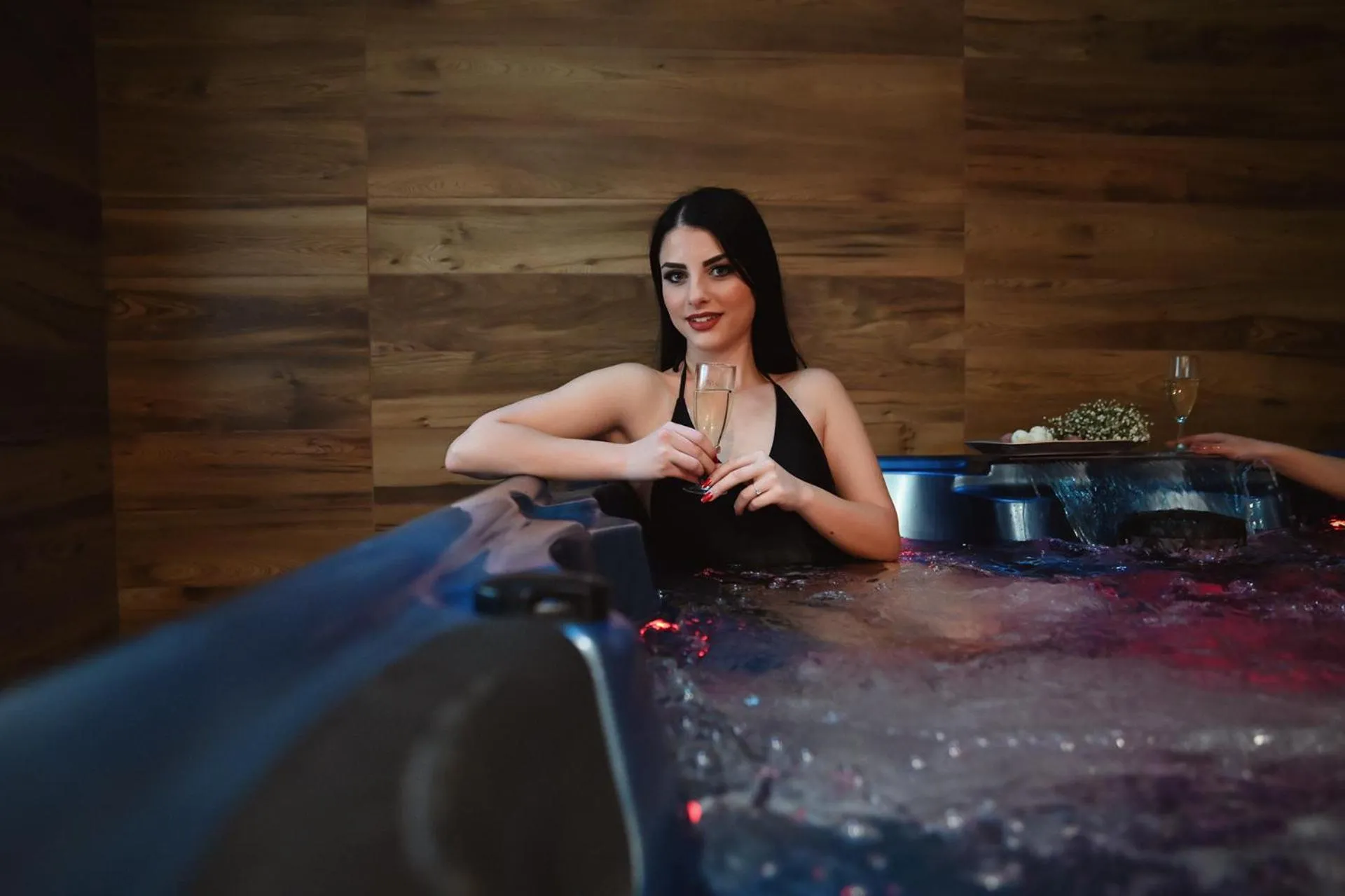 Une femme se détend dans un jacuzzi intérieur avec un verre à la main.