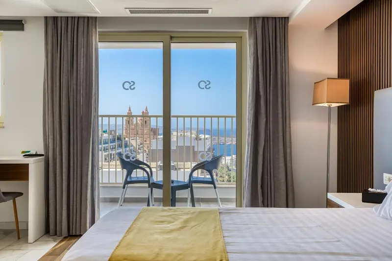 Une chambre avec un lit donnant sur une vue mer et un balcon.